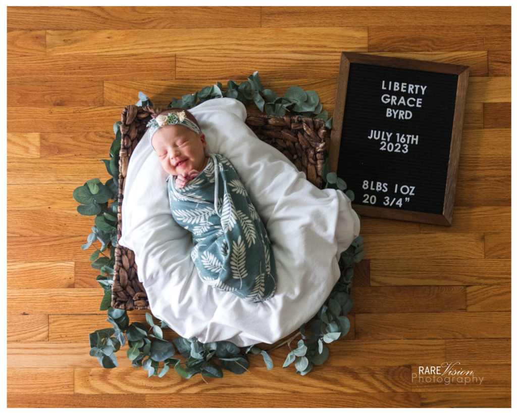 Overhead image of newborn girl with letter board