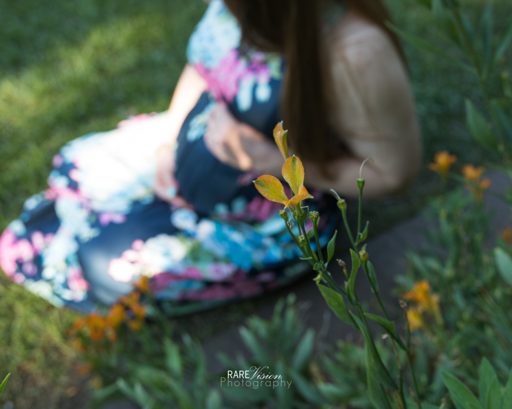 Detail shot of flower inside hosta garden with mom holding her baby Lucy bump in background