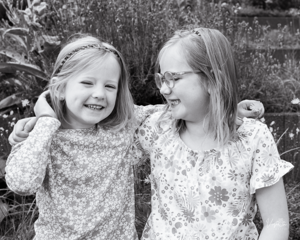Sisters laughing and smiling, one looking at camera