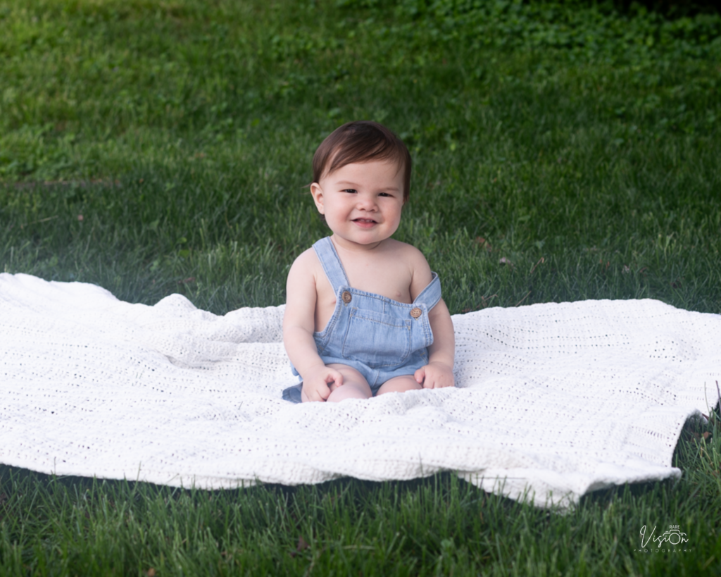 Image of boy sitting on blanket with smile