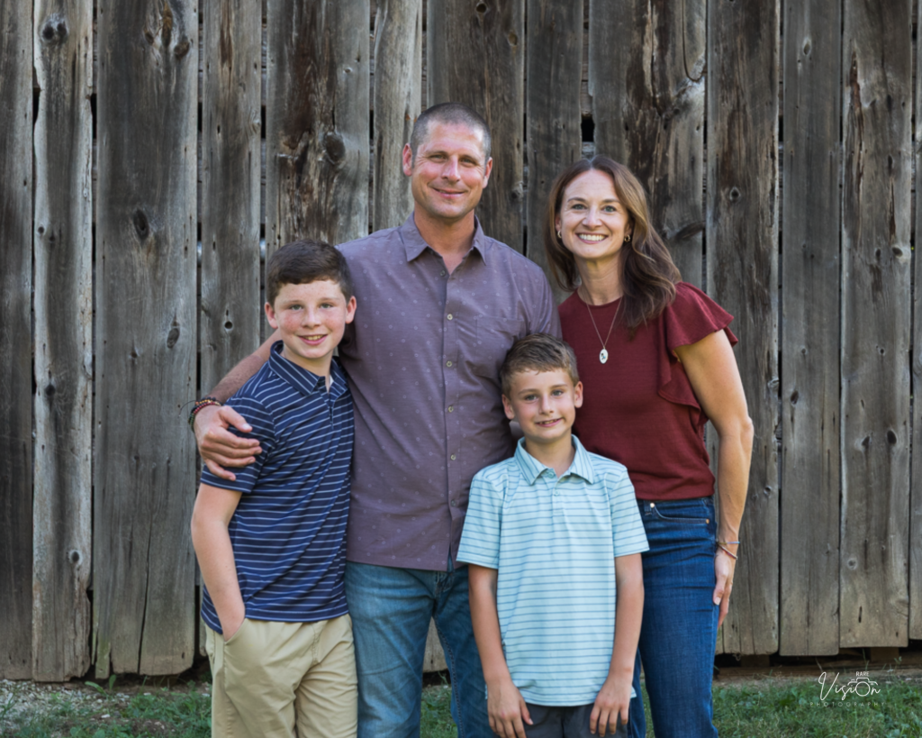 Image of family of four smiling at camera
